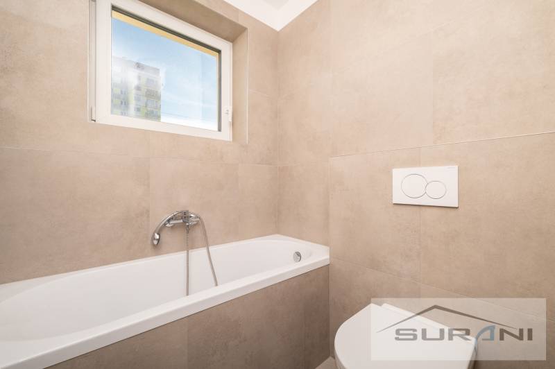 Bathroom with a bathtub and a window in a 2-room apartment, tiles with a beige decor.