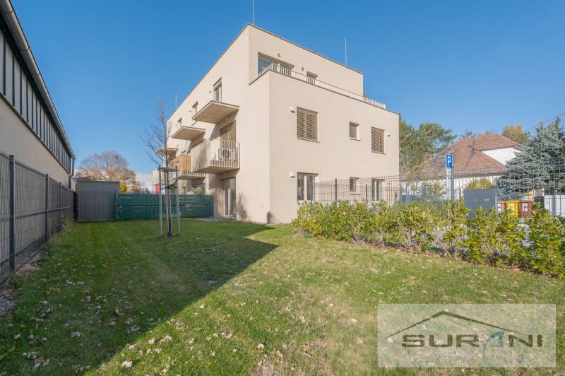 A building with two floors, green grass, and blue sky on Železničná Street in Bratislava.