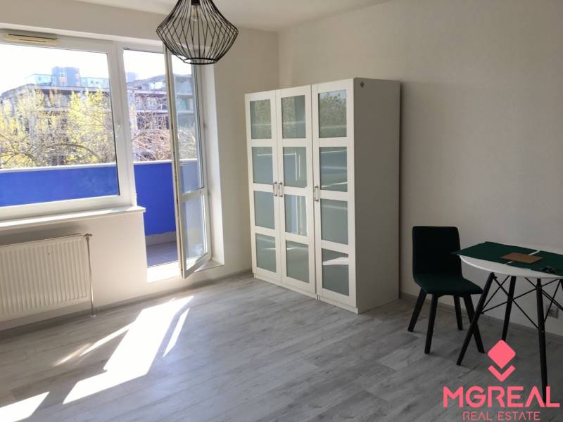 Windows in a 1-room apartment with a wood-decor floor and a view of the balcony.