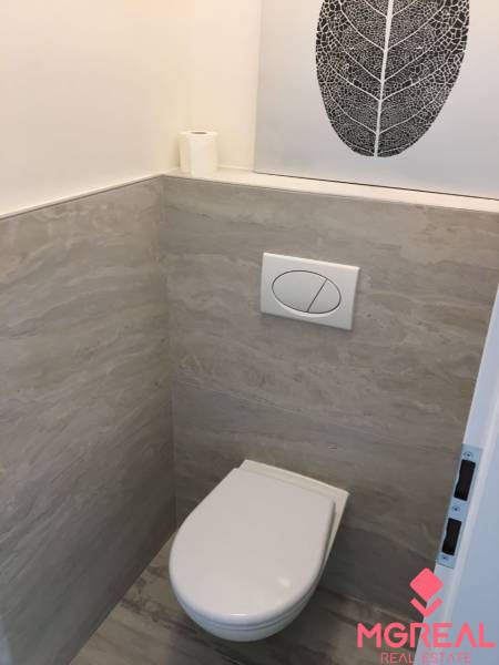 A bathroom with tiles in a studio apartment, a decorative picture of a leaf on the wall.
