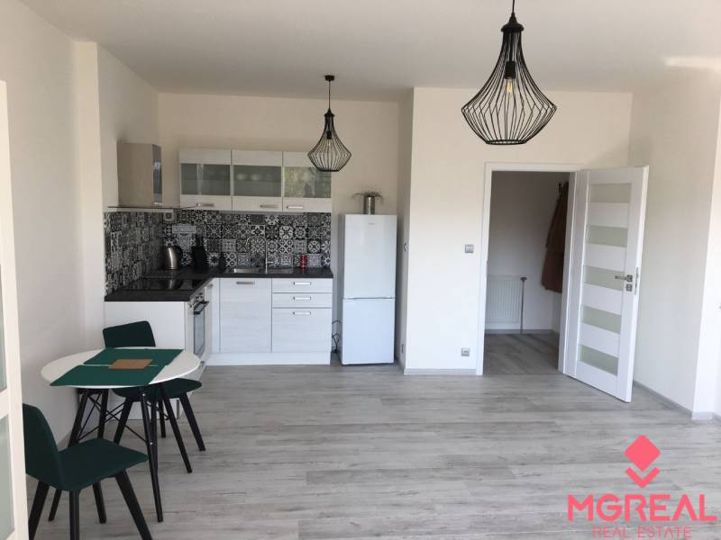 A kitchen in a studio apartment with patterned tiles and a wooden decor floor.