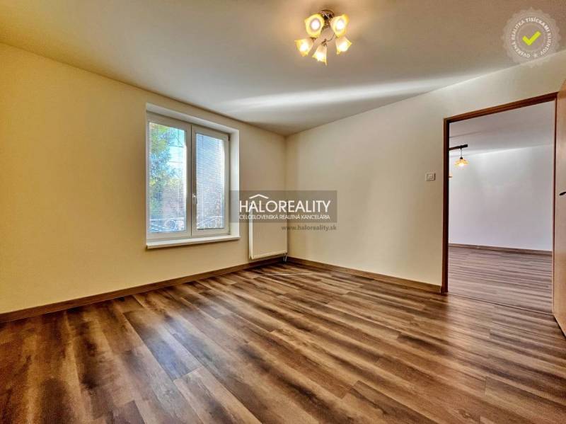 A room in a 3-room apartment with a wooden decor floor and a large window.