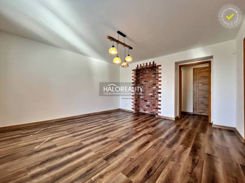Living room in a three-room apartment with a wooden decor floor and a brick wall.