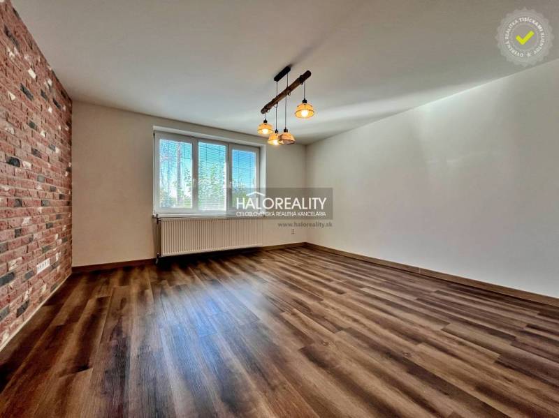 A room in a 3-room apartment with a wooden decor floor and a brick wall cladding.