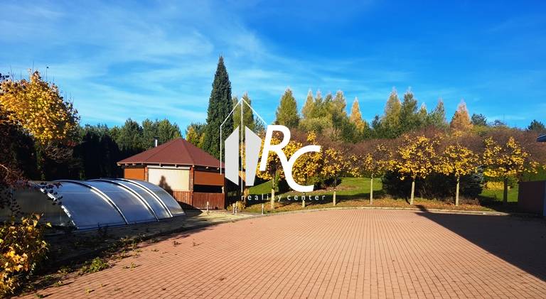 A view of the garden of a family house in Necpaly with a paved area and a swimming pool.