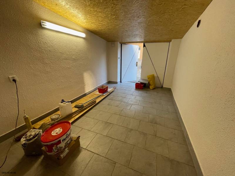 Garages with tools and lighting, floor with wooden decor, open doors to daylight.