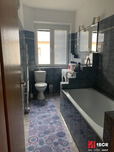 A bathroom with blue tiles and a bathtub in a 2-room apartment.