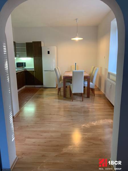 Dining area with wood-patterned flooring in a 2-room apartment, table and four chairs.