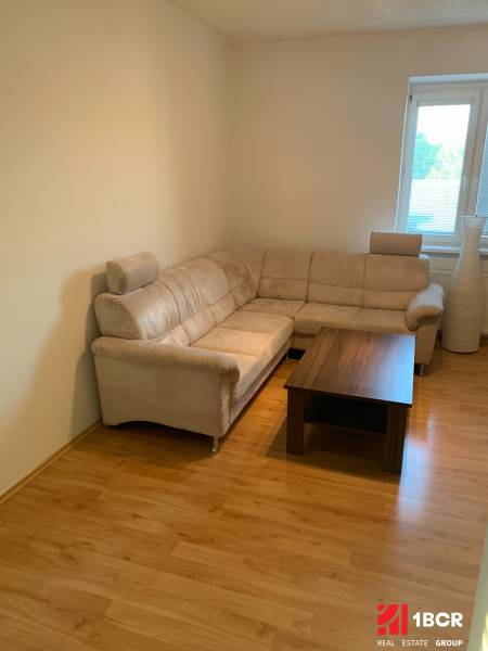 Living room in a two-room apartment with a corner sofa and a floor with a wooden decor.