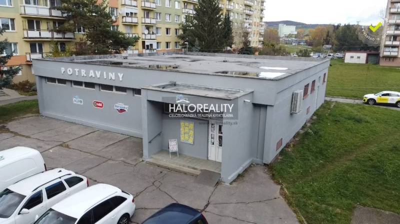 A commercial building in Rimavská Sobota, surrounded by apartment blocks and parked cars.