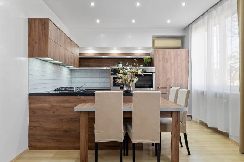 A kitchen in a 2-room apartment with wooden decor and light furniture.