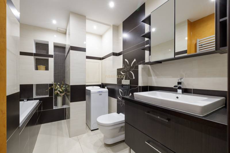 Bathroom in a 2-room apartment with a shower, washing machine, and sink.