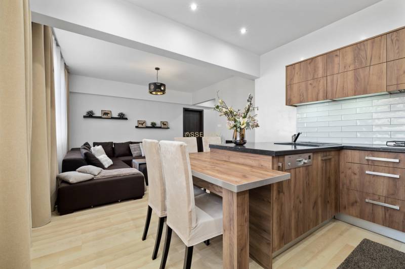 Living room and kitchen with wood-patterned flooring in a two-room apartment.