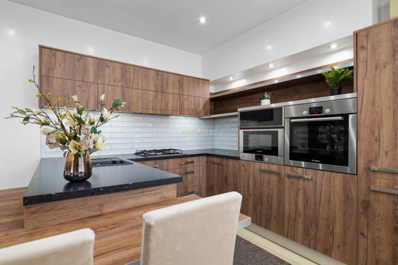 Kitchen in a 2-room apartment, wooden decor, white tiles, built-in appliances.