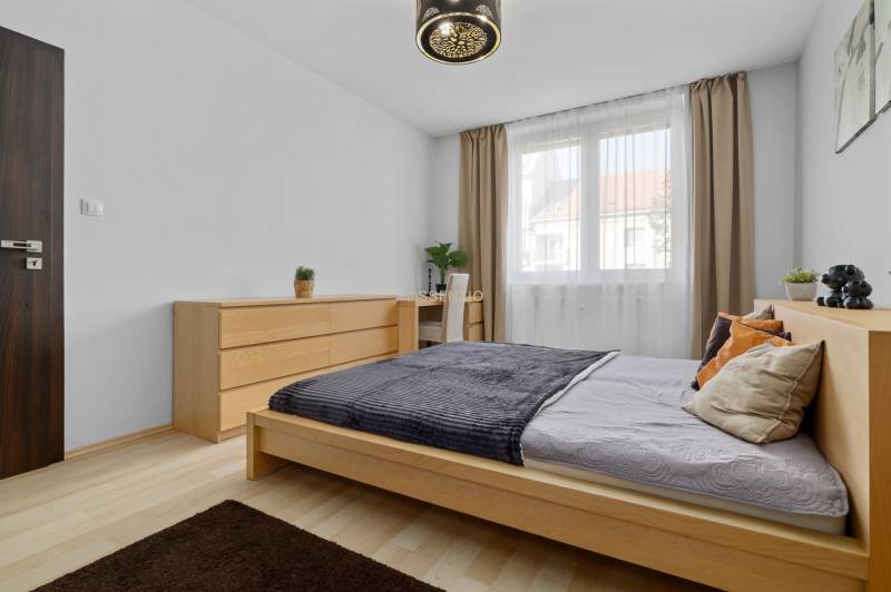 Bedroom with a bed and a dresser in a two-room apartment, floor with wood decor.