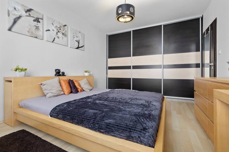 Bedroom in a 2-room apartment with a bed, wardrobe, and decorations, floor with wooden decor.