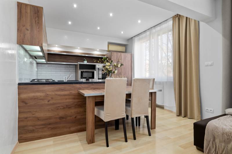 Kitchen in a 2-room apartment with a dining area and a wooden-patterned floor.