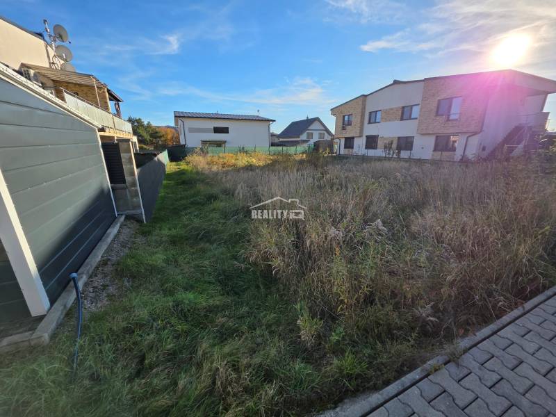 Plots - housing in Bytča with adjacent modern houses and a blue sky.