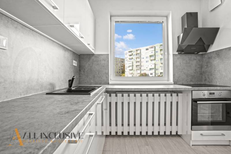 A kitchen in a 2-room apartment with a view and a wooden decor floor.