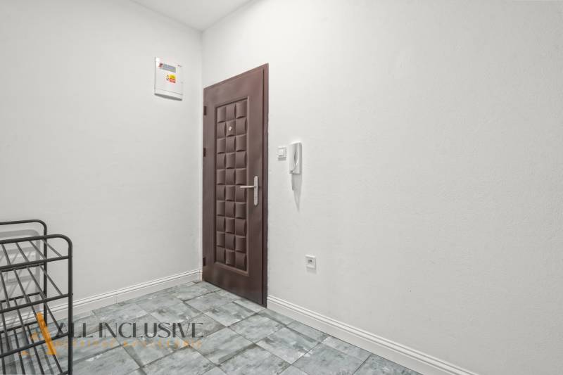 A white hallway with dark doors and tiles in a 2-room apartment.