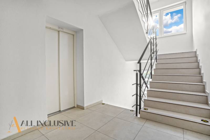 A staircase with light paneling and an elevator in a 2-room apartment.