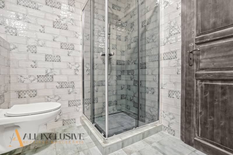 A bathroom in a 2-room apartment with a toilet and a shower, tiled with decorative tiles.