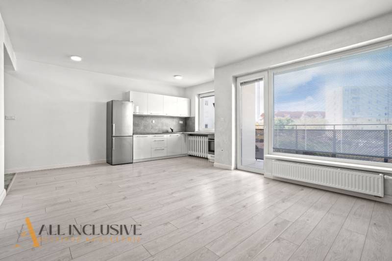 Spacious kitchen in a 2-room apartment with a wooden decor floor and a large window.