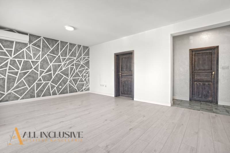 Living room with wood-patterned flooring and a geometric wall in a 2-room apartment.
