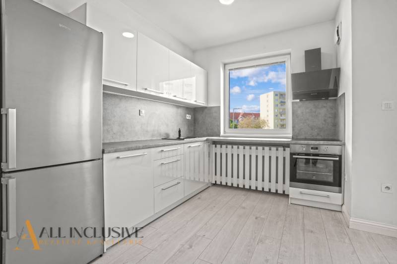 A kitchen with a wood-patterned floor in a 2-room apartment with modern furnishings.