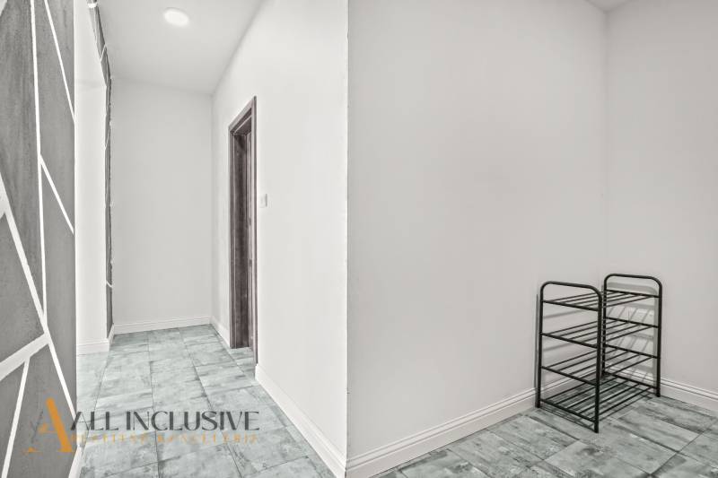 A hallway in a 2-room apartment with a wooden decor floor and a shoe rack.