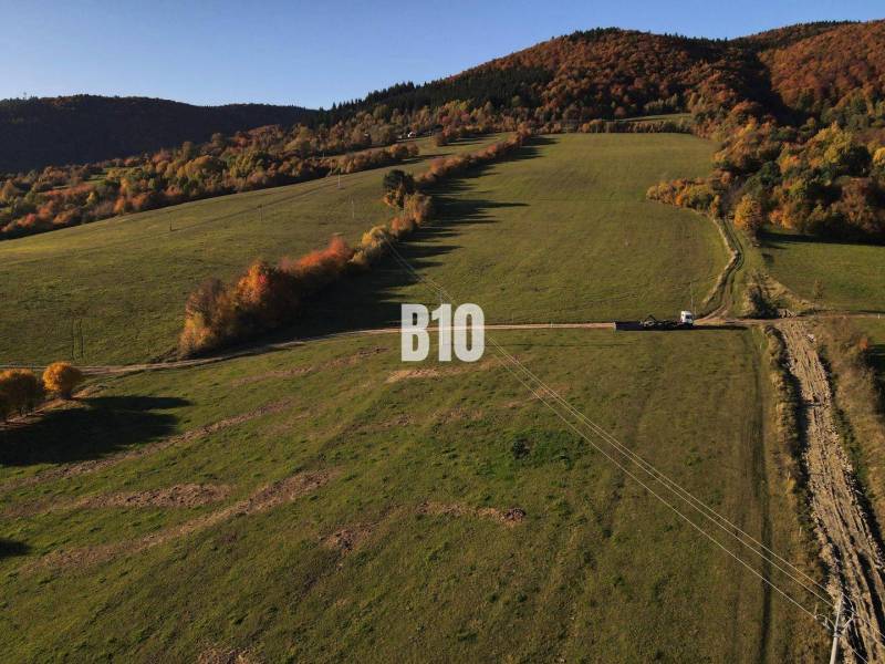 A landscape with residential plots in Petrovice, surrounded by hills and forests in autumn.