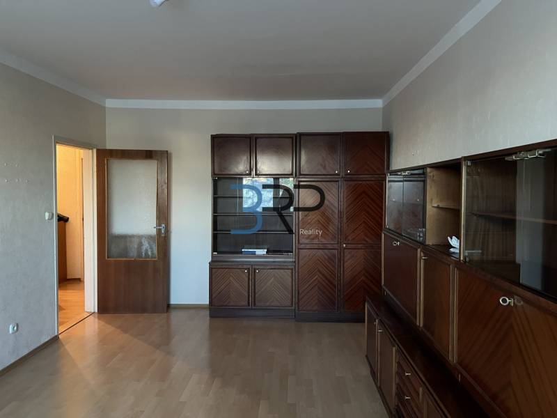 Living room in a two-room apartment with a large wooden living room set and a floor with a wooden decor.
