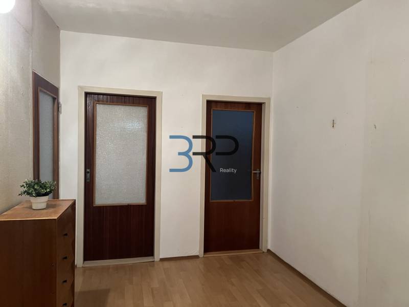 A hallway in a 2-room apartment with a wooden decor floor and two wooden doors.
