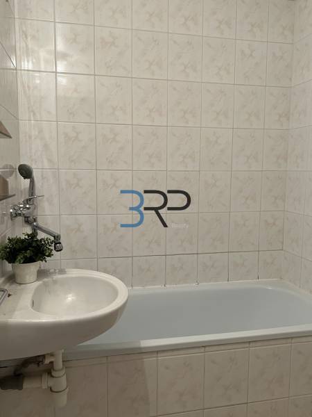 A bathroom with a bathtub and a sink in a 2-room apartment, tiled with tiles.