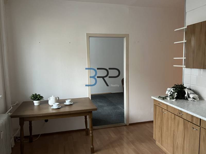 A kitchen in a 2-room apartment with a wooden decor floor, a table, and dishes.