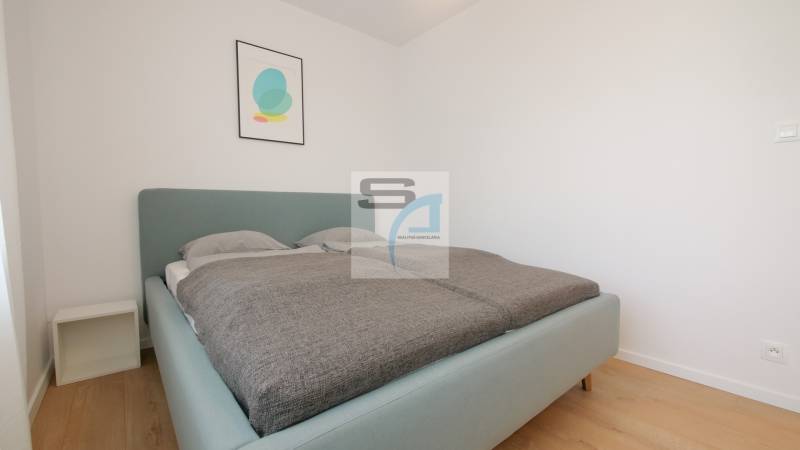 Bedroom with a bed and minimalist decoration in a 2-room apartment, floor with wooden decor.