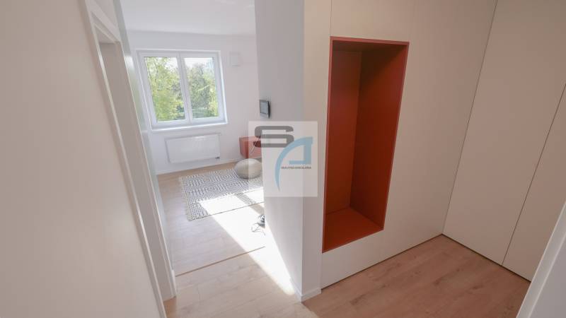 A hallway in a 2-room apartment with a wooden decor floor and a view into the room.