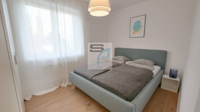 A bedroom with a large bed, curtains, and a wooden decor floor in a 2-room apartment.