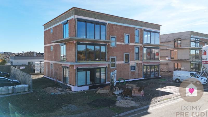A new building on Dúhová Street in Slovenský Grob with glass walls and a parking lot.