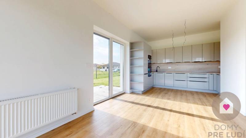 Kitchen and living area in a 3-room apartment with large windows and a view of greenery.