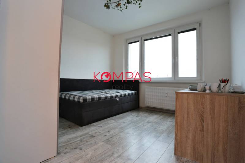 A room in a 3-room apartment, floor with wooden decor, sofa and dresser.