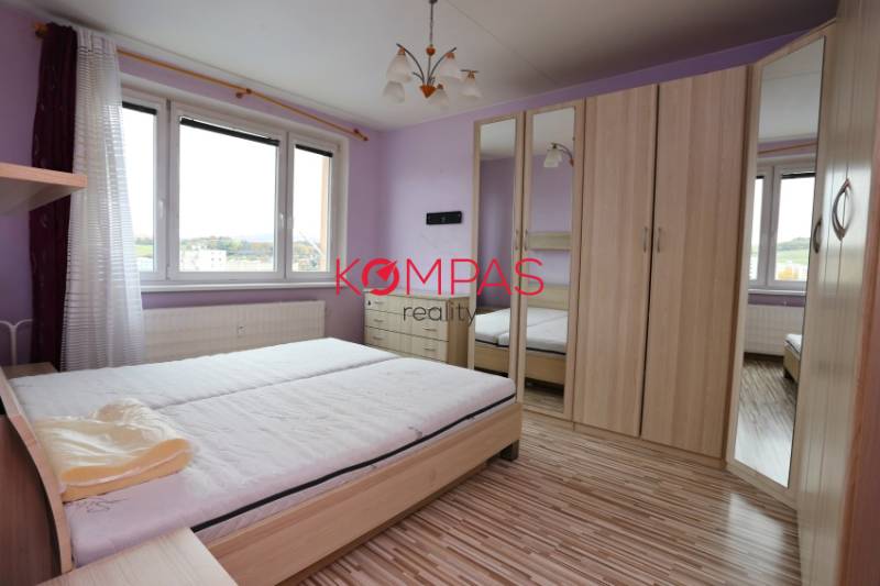 A bright bedroom with wood-patterned flooring in a 3-room apartment.