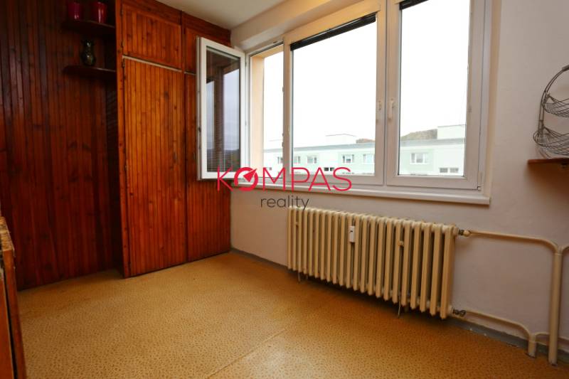 A room with wooden paneling and a radiator in a 3-room apartment.