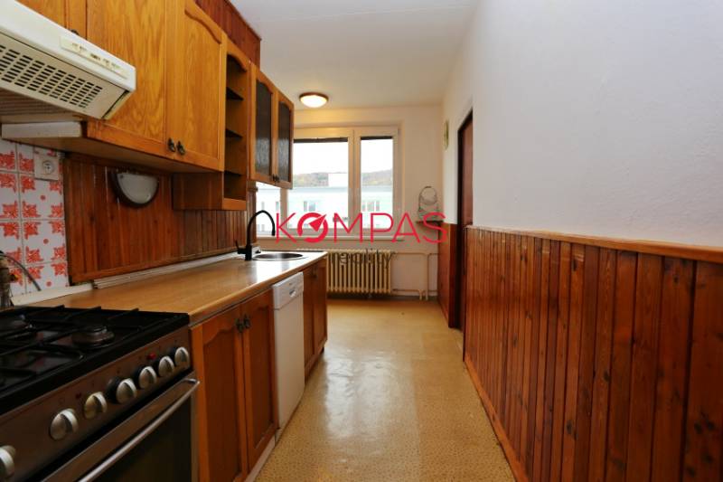 A kitchen in a 3-room apartment with wooden paneling and a gas stove.