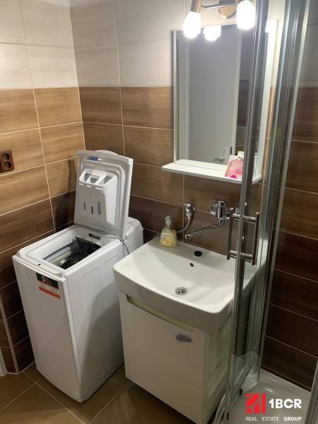 A bathroom in a 2-room apartment with a washing machine and a shower.