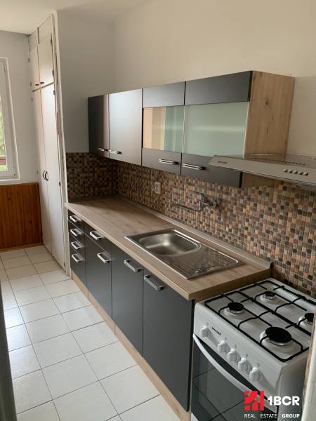 A kitchen in a 2-room apartment with a white tiled floor and a kitchen unit.