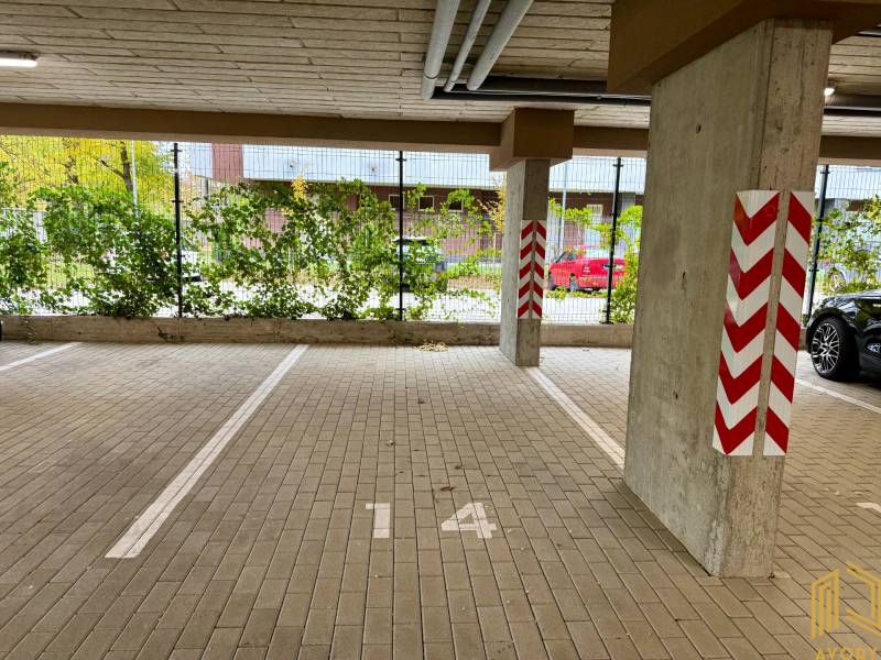 Inside a garage with parking spaces and marked pillars, floor with tiles.