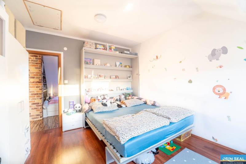 Children's room in a two-room apartment with a bed, shelves, and a wooden decor floor.