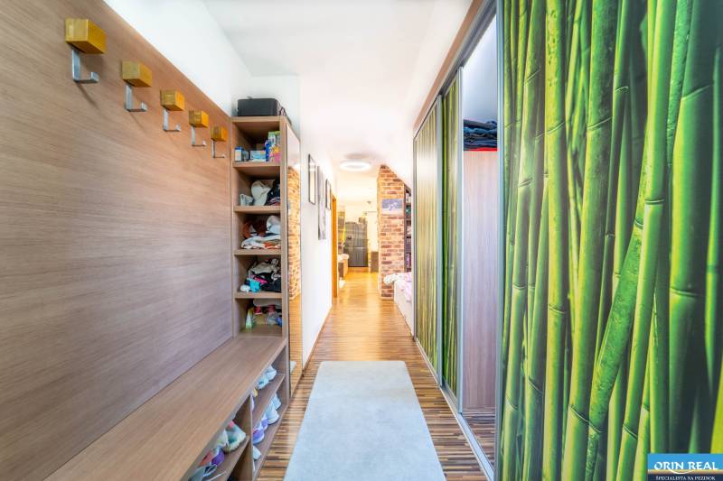 A hallway in a 2-room apartment with a wooden decor floor and storage space.
