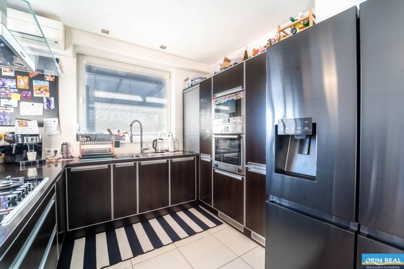 Kitchen in a 2-room apartment with dark cabinets and a spacious refrigerator.